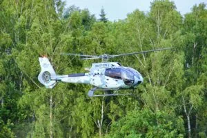 Futuristic helicopter flying above a forest, symbolizing innovation in technology and transport.