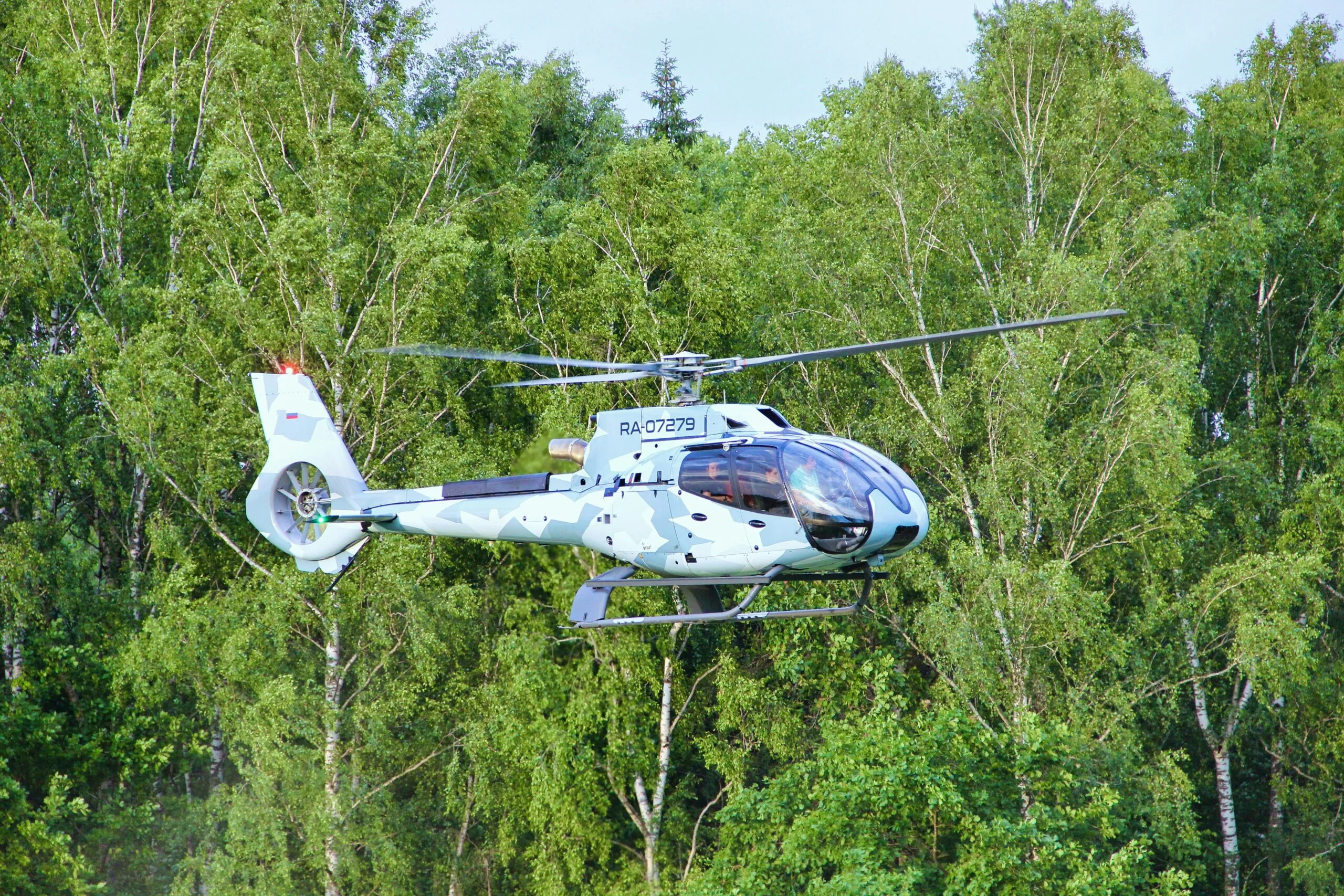 Futuristic helicopter flying above a forest, symbolizing innovation in technology and transport.